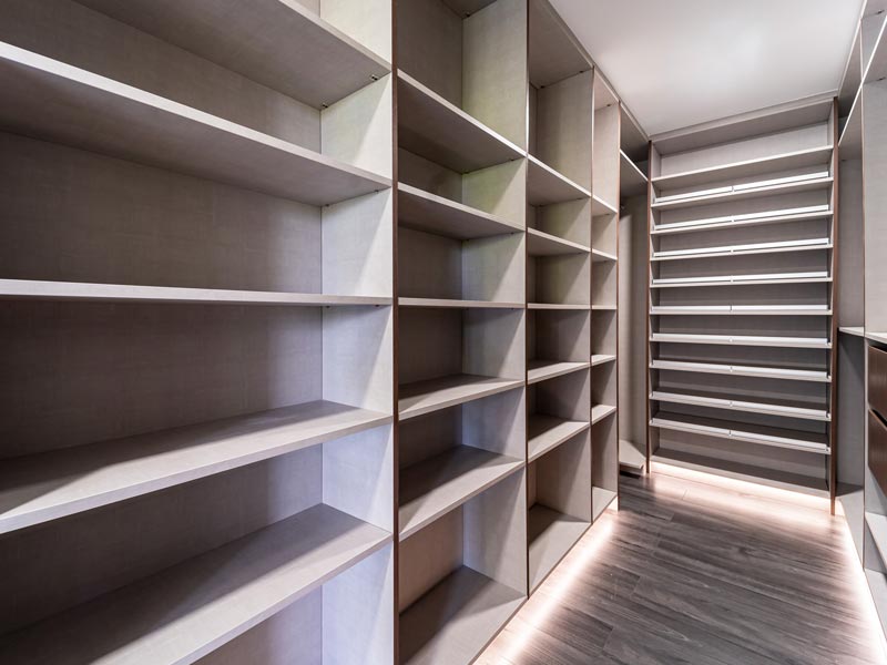 Walk-in closet with full-height open shelving on both walls, shoe shelving at the far end and LED floor lighting