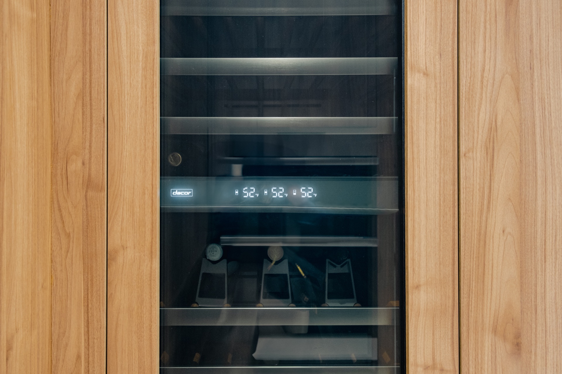 Integrated wine column built into the walnut panelling, its display reading 52 degrees.