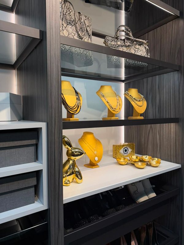 Small closet with shallow drawers and open shelves arranged for jewelry, handbags, and accessories