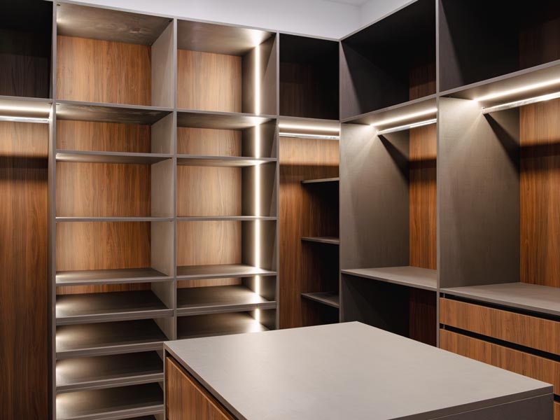 Closet with full-height storage, LED-lit shelving on both walls, base drawers, and a central island