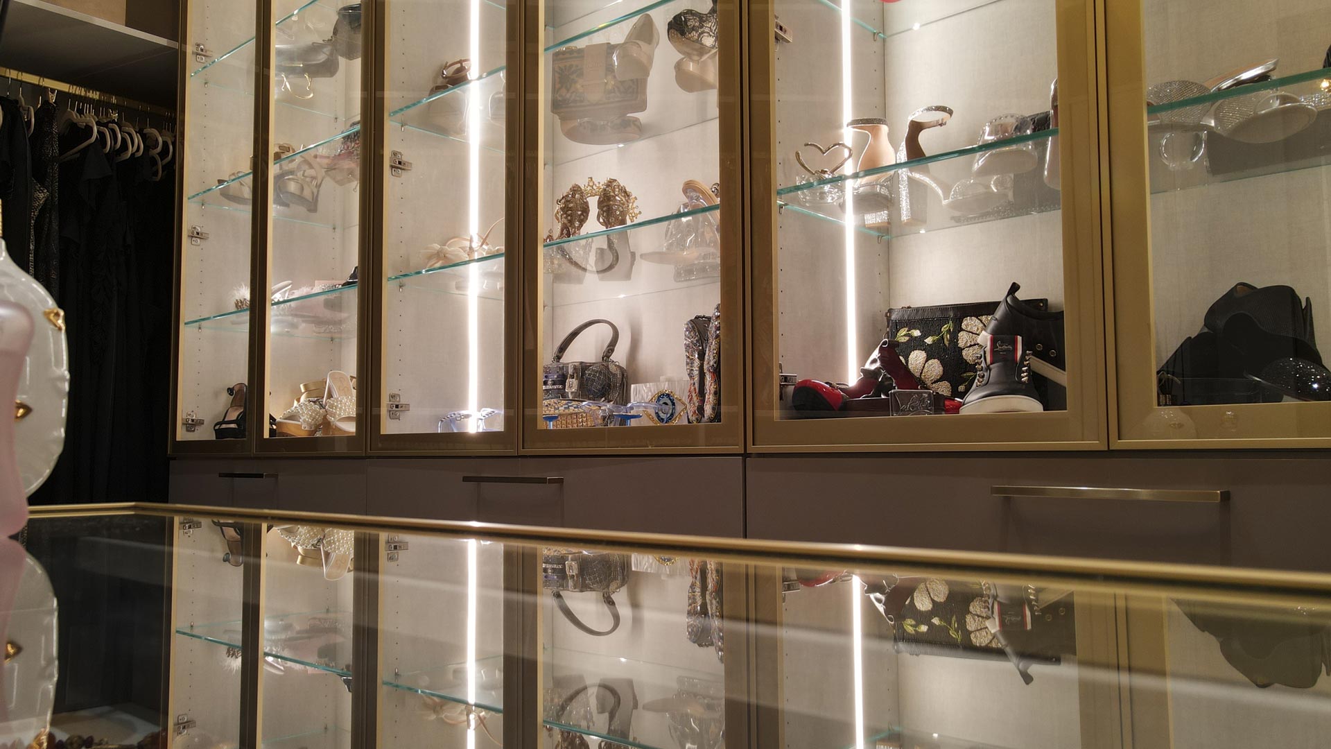 Walk-in closet in Pembroke Pines, Florida, with lit glass display cabinets above a glass-topped counter