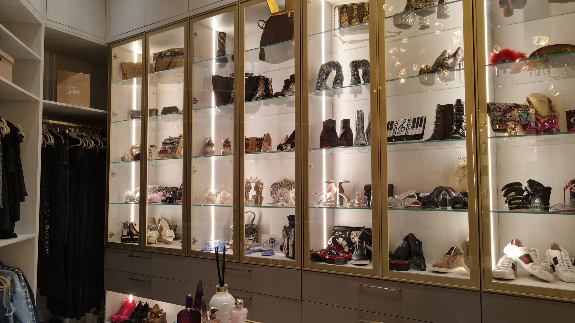 Walk-in closet designed for a client in Pembroke Pines, Florida, with lit glass display cabinets over drawers