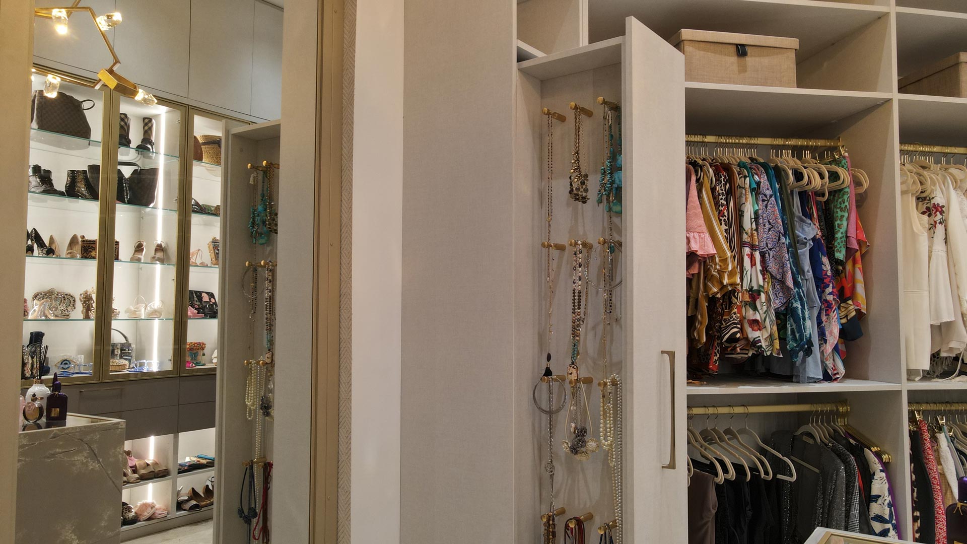 Walk-in closet with a pull-out jewelry panel, stacked hanging zones, and upper shelves for seasonal storage