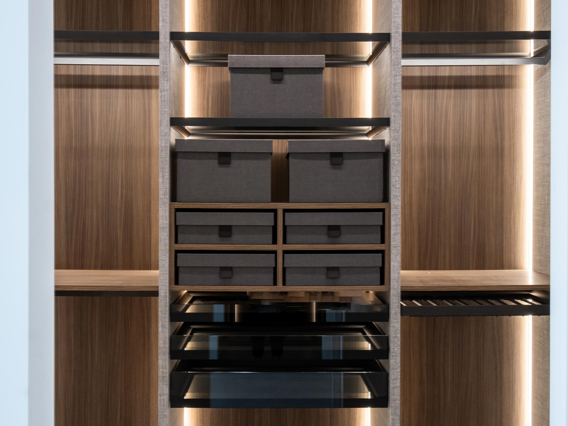 Small closet with shallow drawers and open shelves, fabric storage boxes, and pull-out trays in walnut
