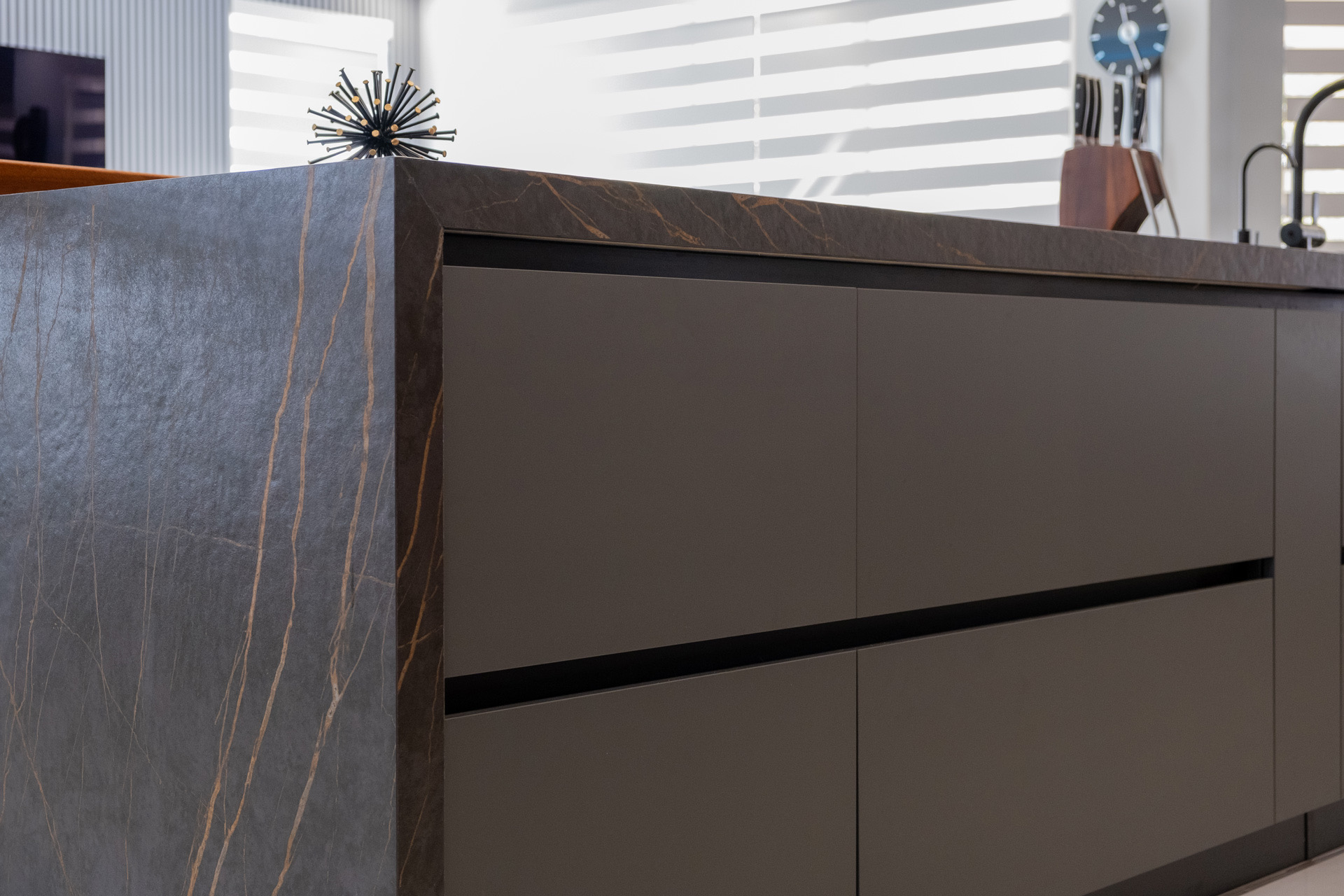 Custom Miami kitchen with graphite matte handleless cabinetry and a dark stone waterfall island.