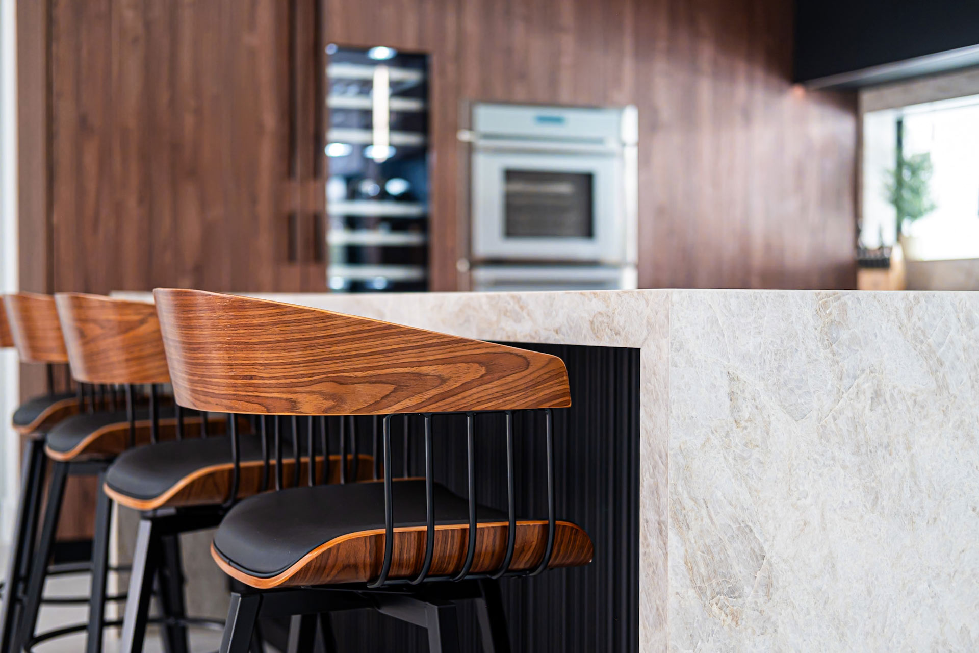 Custom kitchen design in Miami-Dade with a quartzite waterfall island, walnut cabinetry, bar seating, and built-in wall ovens