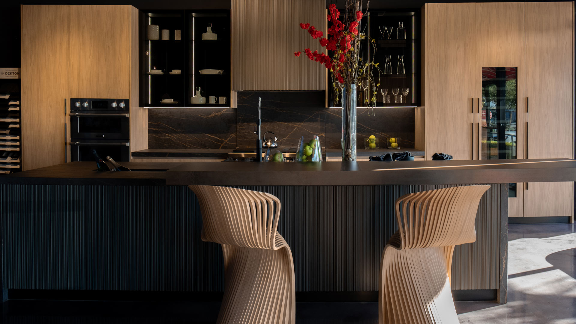 Custom kitchen island in South Florida with sculptural bar seating, walnut cabinetry, and a waterfall countertop