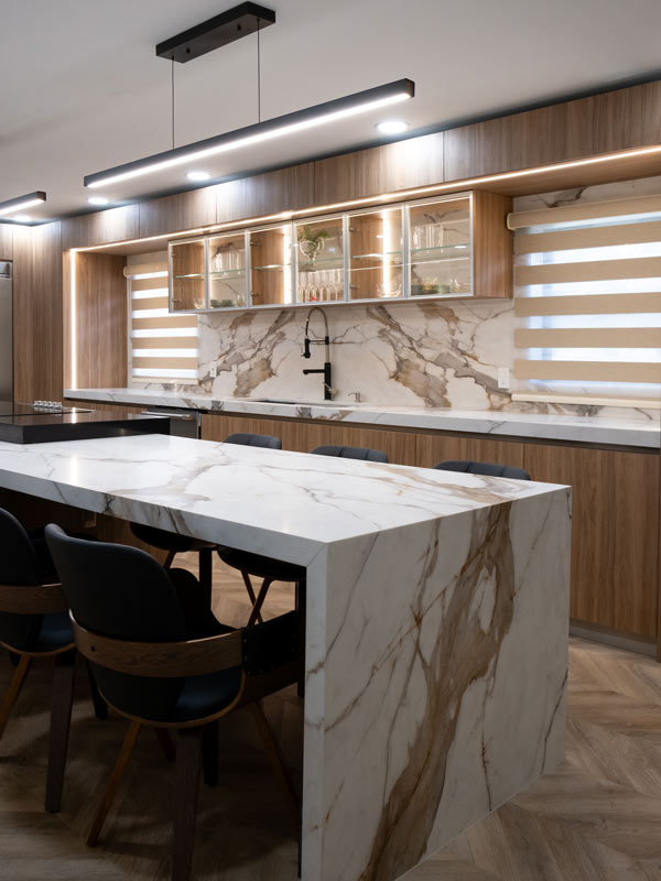 Custom kitchen with a Calacatta marble waterfall island, glass-front cabinetry, and dining seating designed for a Doral home