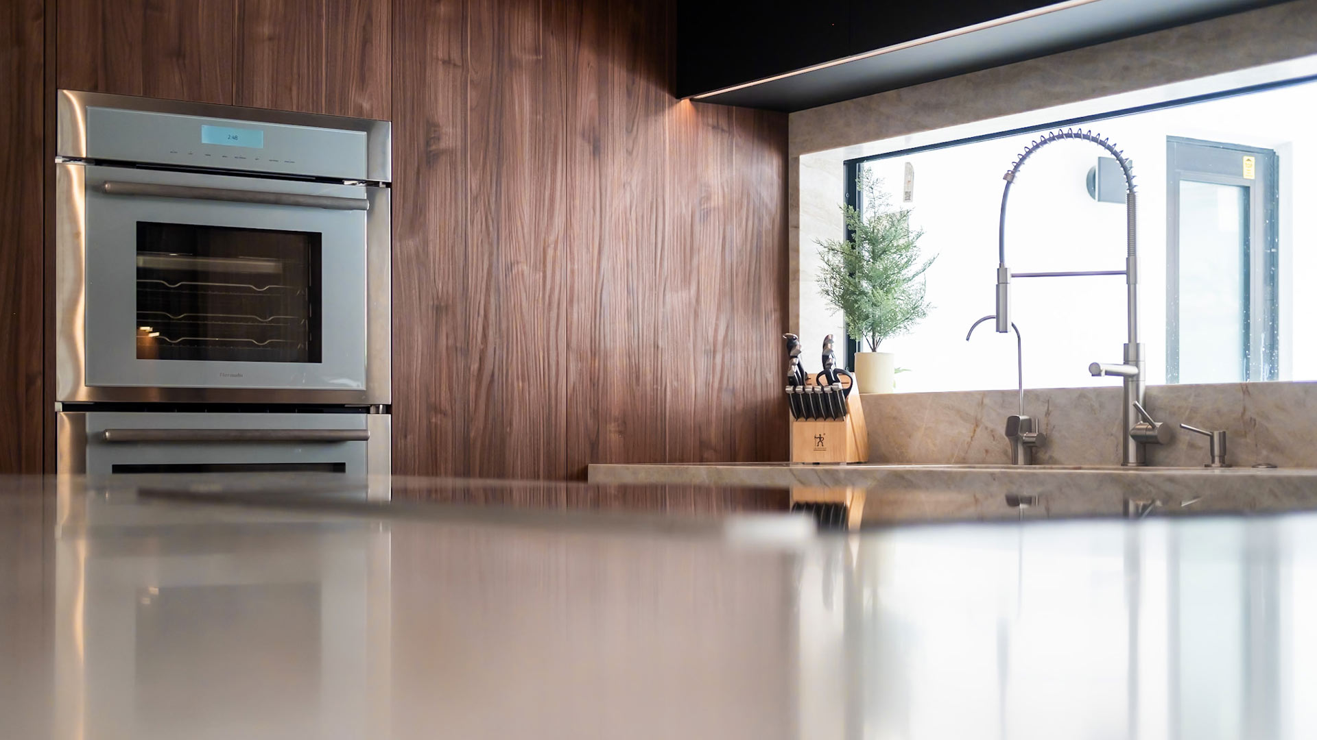 Contemporary custom kitchen in South Florida with walnut cabinetry, quartzite countertops, and a professional faucet by a bright window
