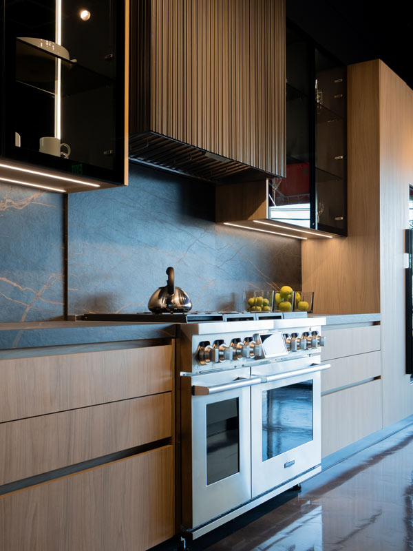 Luxury kitchen design in Doral with a professional range, light oak cabinetry, and a natural stone backsplash